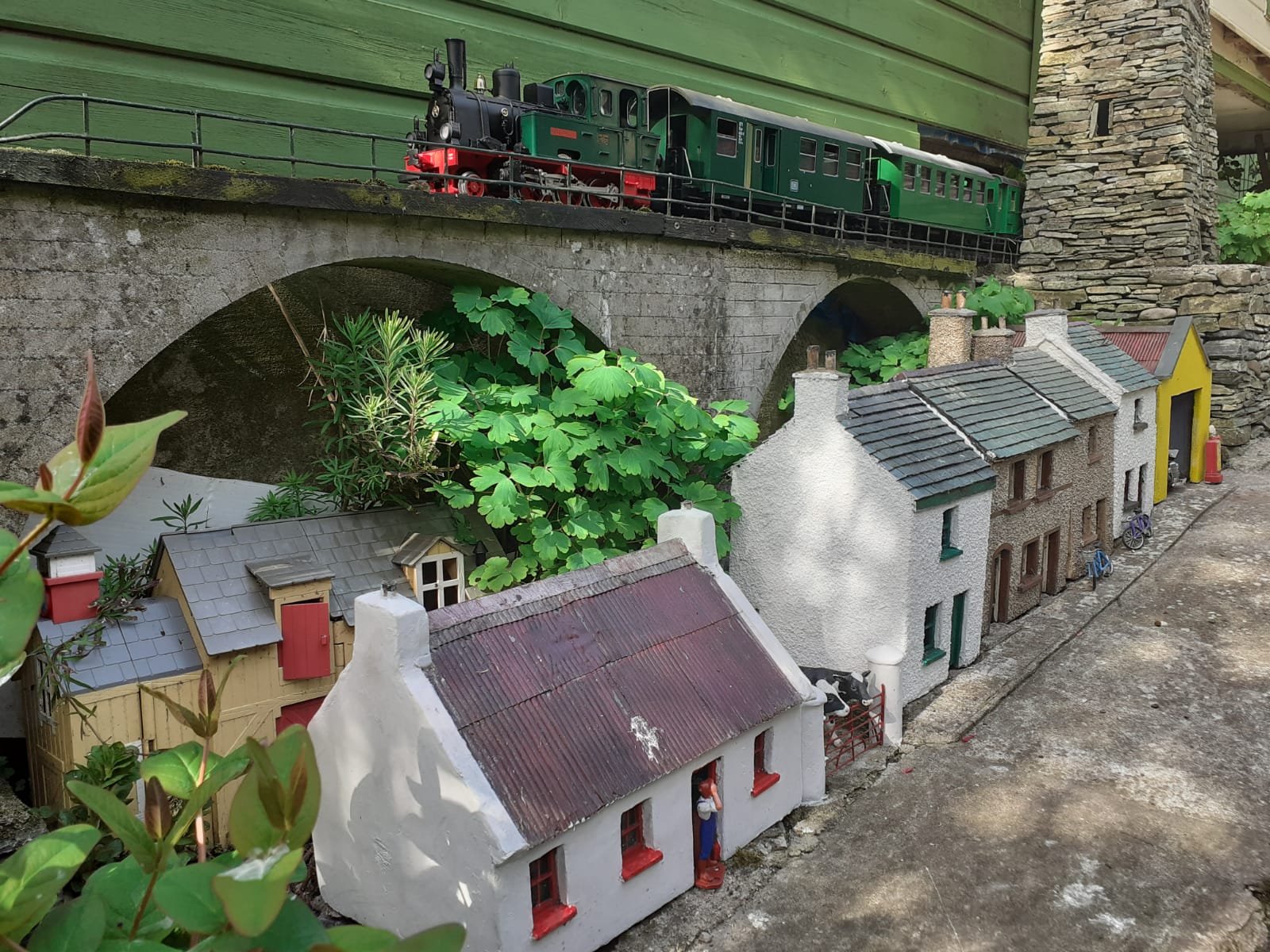 LGB Spreewald has just left Ballinacraig with a service to Derrylecka. The viaduct looks imposing as it towers over the locals